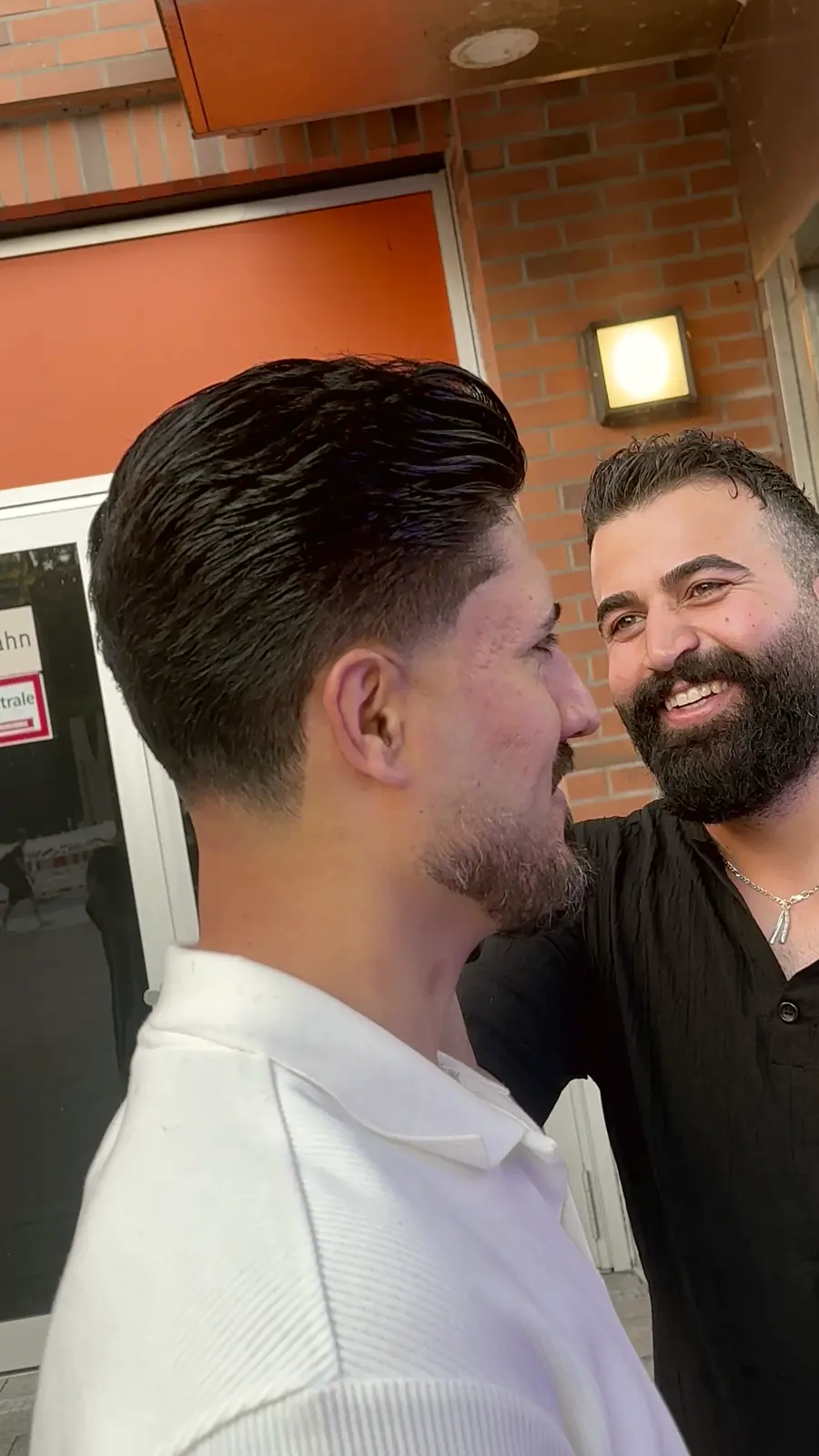 Kunde mit frischem Schnitt, daneben lachend sein Barbier